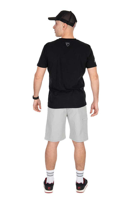 Hombre de espaldas con pantalón corto gris Lightweight de Fox Rage, camiseta negra y gorra, listo para pescar.